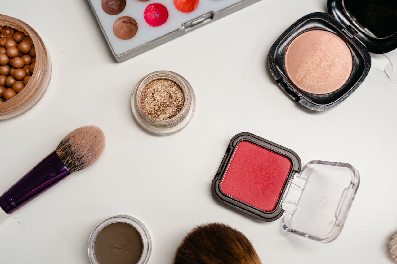 why-choose-us Flat lay of various makeup products including brushes, powders, and creams on a white surface.